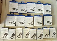 Photo showing 10 boxed Insignia HDMI to DVI-D cables and 8 boxed Insignia 3.5mm FM transmitters arranged in rows on a surface.