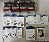 Top view of lot laid out on table showing four Rocketfish HDMI splitters, multiple Insignia HDMI to VGA adapters, a Mini DP to HDMI cable, a USB A to B cable, and three USB to Ethernet adapters, all in original packaging