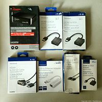 Photo shows seven boxed items: Rocketfish 2-output HDMI splitter, two Insignia HDMI to VGA adapters, one Insignia HDMI to DVI cable, one Insignia USB to Ethernet adapter, Insignia 3ft HDMI cable, and an additional Insignia HDMI to VGA adapter.