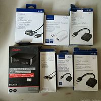 Photo of Rocketfish HDMI splitter and various Insignia adapters and cables in original packaging, showing quantity and condition as open box returns.
