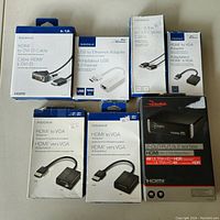 Photo of the 7 unopened boxed items including Insignia and Rocketfish branded HDMI and USB adapters and cables.