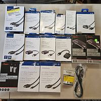 Photo showing various packaged cables and adapters laid out on a flat surface. Includes Insignia Mini DisplayPort to HDMI cables, Rocketfish HDMI to VGA adapters, and other cables with clear brand and length information.