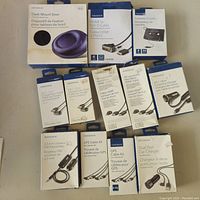 Photo of the boxed Insignia electronic cables and adapters arranged on a surface showing each product's packaging and label.