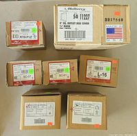 Photo showing multiple sealed boxes with labels detailing quantities and types of EMT connectors and outlet covers.