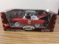 Side view of the diecast model and packaging showing red car with Fire Chief decals, open hood showing engine detail.