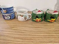 All six items displayed together: two Looney Tunes bowls stacked, one onion soup bowl and two dinosaur Christmas mugs.