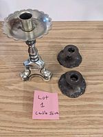 Lot includes one single silver-tone metal candlestick with a scalloped tray and two smaller dark metal candlesticks with engraved bases.