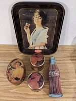 Full view of four Coca-Cola tins and vintage metal tray on wooden surface