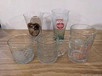 Five different glass drinking glasses displayed in a row with various prints and textures