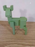 Front view of the green geometric deer statue placed on a wooden surface.