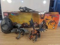 Front view of two Mega Bloks dragons buildable figures and a large dark dragon egg, displayed with packaging boxes in background.