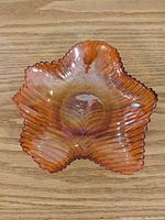 Top down view of orange glass leaf-shaped dish showing ribbed leaf vein texture and five lobes of the leaf.