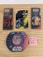 Photo shows four Star Wars items including a Darth Maul flip top watch, Darth Vader figure, another Star Wars watch, and a circular die-cast metal item in original packaging, accompanied by a pink note labeled Star Wars Lot #3.