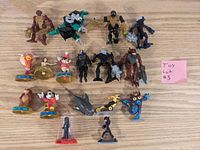 Top-down view of the entire toy lot showing Bionicle figures, Disney character figures, shark and other toys on a wooden surface.