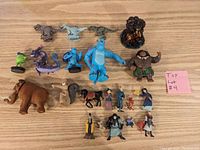 Photo showing full collection of 22 assorted small character toys from various animated movies arranged on a wooden surface.