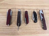 Overhead view of all five kitchen utility items arranged side by side on wooden surface, showing variety in types and colors.