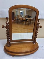 Full view of antique dresser top mirror with wooden frame, showing arched rectangular mirror and turned side supports with finials and adjustment knobs.