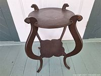 Front angled view of two-tier round wood stand showing overall shape and patina