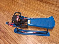 Full sled with blue seat and black metal frame. Steering handlebars visible. Shows overall condition and design.