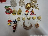 Photo of various Christmas decorations including dolls, angels, drums, and assorted ornaments arranged on a white surface.