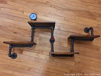 Overhead view of the entire industrial style shelf, showing the arrangement of the three wooden shelves supported by black metal piping, pressure gauge and red valve handle visible.