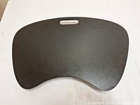 Top view of the black lap desk's hard writing surface with hand-grip cutout.