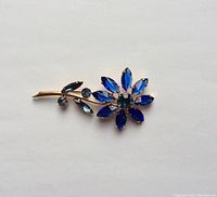 Photo showing the large flower brooch with blue glass petals and rhinestones on gold-tone stem