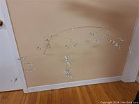 Full view of sea gull mobile displayed against a beige wall and wooden floor.