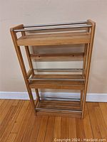 Wood and metal storage rack shown from a top side angle, showing the three wooden shelves and metal bars.