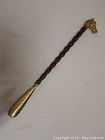 Full view of the 23 inch shoe horn showing the carved wooden shaft and brass shoe horn end.