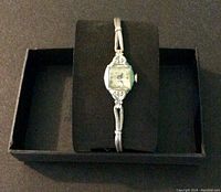 Full view of watch on black display cushion in box