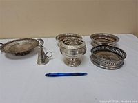 Vintage silver plated assortment: oval tray, vase with frog, candle snuffer, three round wine bottle coasters with pierced detail.