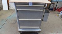 Front view of aluminum tool box with wood top and side trays.