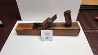 Photo of the antique wooden block planer showing the top side with the metal blade and wooden handles.