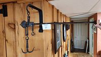 Overall side view of the antique hanging steel weight scale mounted on wooden wall beam, showing the long arm and triple hook.