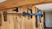 Full view of the large antique hanging scale mounted on wood wall, showing entire 41 inch long steel beam with hook ends and mounting bracket.