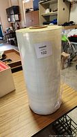 Side view of the full large roll of plastic wrap sitting on a table showing its height and diameter.