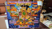 Full view of the Alley Cats colorful pinball back plate with cartoon cats and score windows.