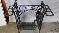 Side front view of cast iron sewing machine base with treadle pedal and side mounts