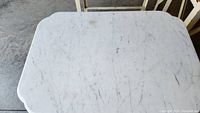 Top view showing white marble table top with rounded corners and natural veining.