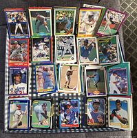 Multiple stacks of colorful vintage baseball cards displayed on a dark checkered surface, showing front card images of various players.