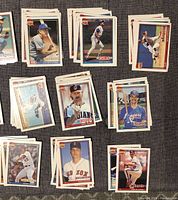 Stacks of 1991 Topps 40 Years of Baseball trading cards featuring players from MLB teams such as Montreal Expos, Chicago Cubs, Cleveland Indians, Los Angeles Dodgers, Cincinnati Reds, Boston Red Sox.
