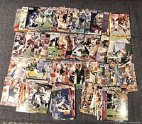 Photo showing a large assortment of NFL Pro-Set trading cards from 1990-1991 scattered on a dark surface. Multiple cards visible with images of players in action and team colors.