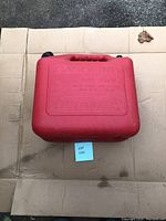 Top view of red plastic gas can showing embossed 'GASOLINE' label and safety instructions, black fill cap, and handle.