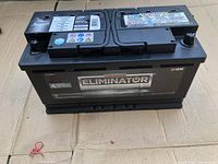 Front view of black Eliminator battery showing brand and size details on a cardboard base.
