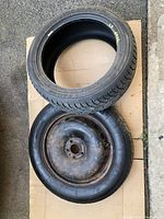 18 inch steel donut spare wheel and 215/50R17 winter tire, shown on cardboard, tire tread visible