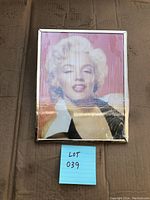 Front view of vintage framed Marilyn Monroe picture with pink background and dark frame, covered in reflective glass.