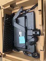Monitor, keyboard, mouse and cables arranged in packaging box showing backside of monitor and accessories