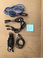 Various electronics wires and cables laid out on cardboard surface including multiple USB-C cables and adapters all tested with continuity.