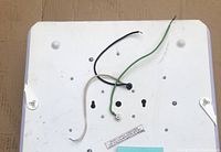 Back of the ceiling light fixture showing three wires (black, white, and green) for electrical connection and mounting points.